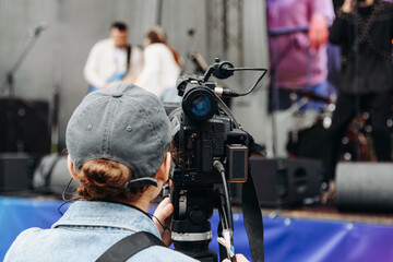 large black video camera on tripod, close-up view, videographer working at music festival in city...
