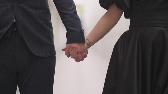 Couple holding hands, fingers intertwined