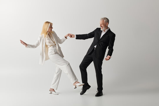 Stylish senior couple enjoys a joyful dance together in elegant attire and timeless love - Powered by Adobe