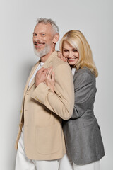 Stylish senior couple sharing love and laughter in trendy attire against a neutral backdrop