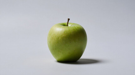 A vibrant green apple sits alone in the center of a light gray background, highlighting its fresh texture and natural gloss