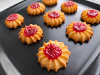 Biscuits, confectionery in the form of daisies with berry jam in the middle. Molded cookies. Close-up photo