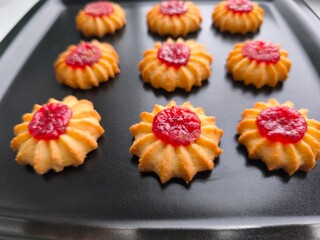 Biscuits, confectionery in the form of daisies with berry jam in the middle. Molded cookies. Close-up photo