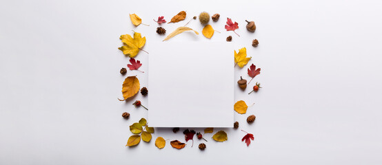 Autumn composition with paper blank and dried leaves on table. Flat lay, top view, copy space