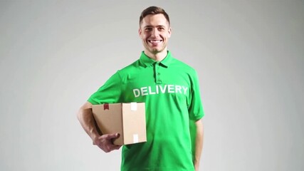 Smiling delivery man wearing green uniform with cardboard parcel box giving a thumbs up gesture on a neutral background. Modern logistics, trustworthy vibe concept,4K.
