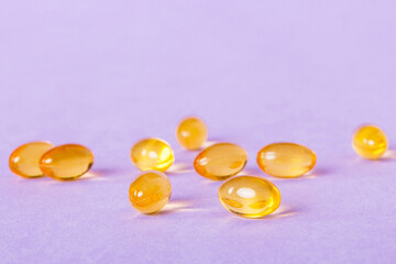 Heap of yellov pills on colored background. Tablets scattered on a table. Pile of red soft gelatin...