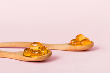 Vitamin omega capsules in a spoon on a colored background. Pills served as a healthy meal. Red soft...