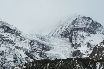 Moody glacier and snowy mountain peaks on a foggy day