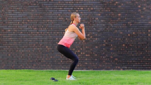 Woman Doing Squats with Dumbbell Outdoors