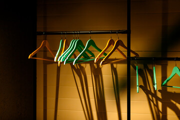 Bright wooden clothes hangers suspended from a metal bar. The shadows from the hangers create an...