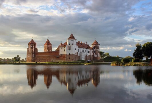 Mir Castle. A castle on the shore of a lake. A summer landscape. Sunset. An ancient medieval fortress. Travel. An architectural monument of the Middle Ages - Mir Castle, Belarus.
