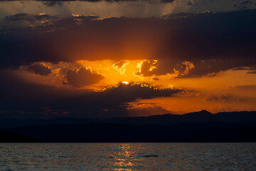 Golden Sunset Over Silhouetted Mountains and Tranquil Waters