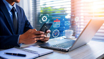 Obraz premium Businessman using a mobile phone and laptop with digital calendar and email icons, representing business communication and schedule management
