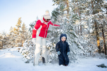 Grandmother shakes snow from tree onto laughing toddler, enjoying winter fun, fresh air, family...