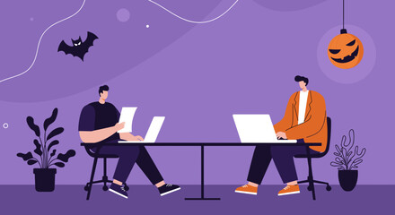 Two colleagues work on laptops at a shared desk in a modern office decorated for Halloween with a pumpkin lantern and bat. Represents seasonal business, remote work, and teamwork.