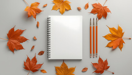 “Blank White Spiral Sketchbook with Paintbrushes, Pencils, and Autumn Leaves – Minimalist Art Workspace Flat Lay”
