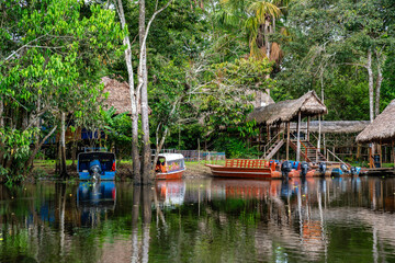 Boote am Anleger einer Lodge inmitten des dichten Amazonas Regenwaldes mit Reflexionen im Wasser