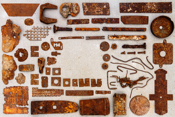 A group of various old rusty bits and pieces arranged on a concrete surface. Old rusty nuts, bolts, nails and other parts flay lay on gray background.