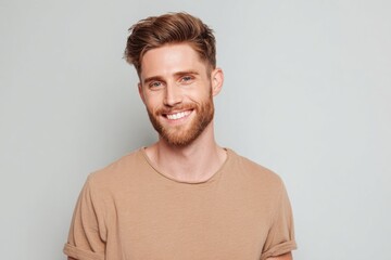 Bright smiling young man with beard and casual beige t-shirt posing indoors.