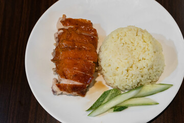 Top view of the delicious chicken rice served with slices of fresh cucumber on a plate.