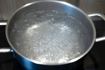 Water are cooked in a stainless steel pot, hot boiling water. Kitchen at home, preparation lunch or for dinner.