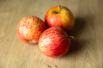 Three ripe red apples on the kitchen table. The friuts are ripe and ready to eat.