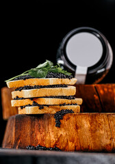 Stacks of fresh bread slices topped with luxurious caviar and fresh herbs showcase a refined culinary experience against a dark backdrop.