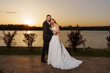 Gentle and happy bride and groom at sunset on the riverbank. Romantic.