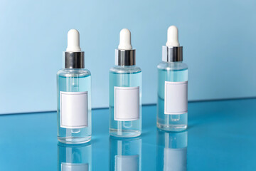Obraz premium three cosmetic glass bottles with serum and few jasmine flowers with shadow on beige 