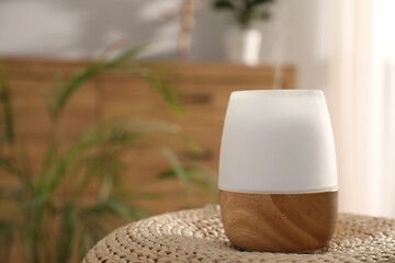 Modern aroma lamp on wicker surface indoors. Space for text