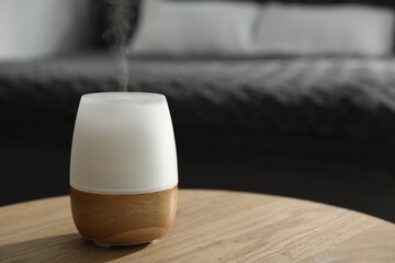 Modern aroma lamp on wooden table indoors. Space for text