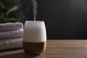 Modern aroma lamp on wooden table indoors. Space for text