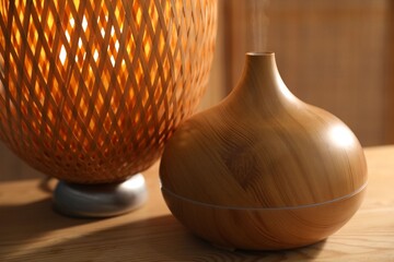 Modern aroma lamp on wooden table indoors, closeup