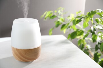 Modern aroma lamp on white wooden table indoors