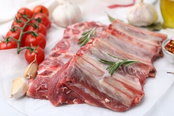 Fresh raw beef ribs, tomatoes and spices on table, closeup