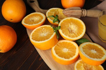 Squeezed oranges with mint and juicer on wooden table