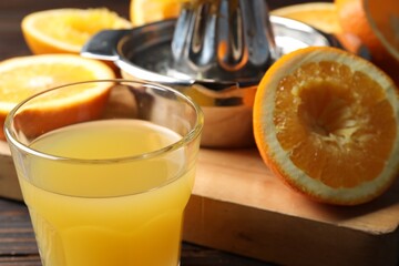 Freshly squeezed orange juice, fruits and juicer on wooden table, selective focus