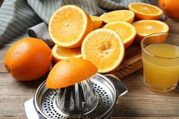 Freshly squeezed orange juice, fruits and juicer on wooden table, closeup