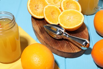 Freshly squeezed orange juice, fruits and juicer on blue wooden table, closeup