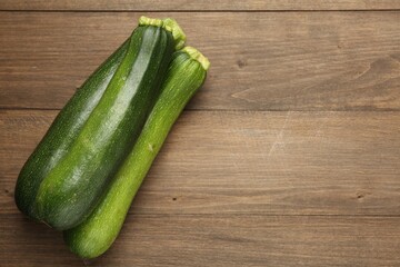 Fresh ripe zucchinis on wooden table, top view. Space for text