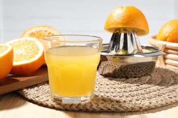 Freshly squeezed orange juice, fruits and juicer on wooden table, closeup