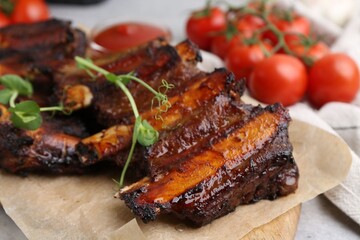 Roasted beef ribs with microgreens and tomatoes on table, closeup
