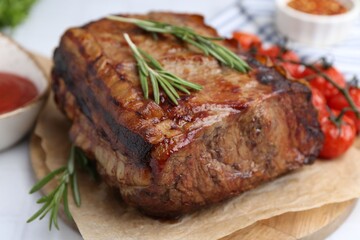 Delicious roast beef with rosemary and tomatoes on table, closeup