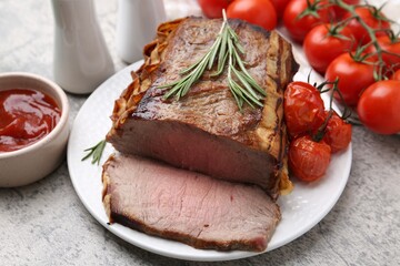Delicious baked beef meat, tomatoes, rosemary and sauce on grey table, closeup