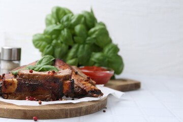 Roasted beef ribs with spices and ketchup on white tiled table, closeup. Space for text