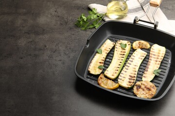 Delicious grilled courgette slices with garlic, lemon and parsley in pan on grey textured table,...