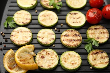Delicious grilled courgette slices with tomatoes, lemon and parsley in pan, above view