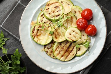 Delicious grilled courgette slices with tomatoes, microgreens and parsley on table, flat lay