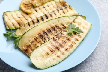 Delicious grilled courgette slices with parsley and lemon on table, closeup