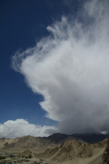 Puffy clouds blue sky. Puffy white clouds against a blue sky over the mountain.